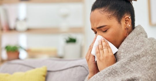 woman blowing nose in house